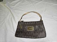 Front of brown MK monogram purse showing logo plaque and strap