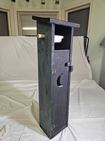 Front view of wooden outhouse toilet paper holder with roll on spindle