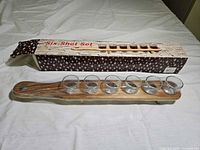 Shot glasses still wrapped on wooden paddle with retail box