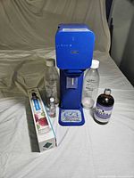 Front view of SodaStream unit, two bottles, boxed CO2, syrup bottles