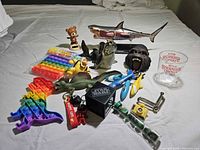All toys laid out including shark model, pop-its, figures, dice, gliders, glass