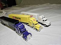 Three transport truck models aligned diagonally showing cabs and trailers
