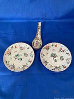 Front view of two plates and spoon showing painted designs