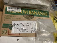 Box containing stack of clear plastic bags with handwritten label indicating 20x21 inches and approx 700 pieces