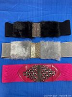 Three belts laid out showing colors and clasp designs