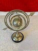 Front view of silver-tone metal armillary sphere on pedestal base
