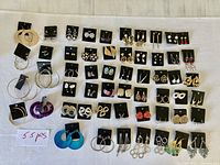 Full layout of 55 pairs of earrings on cloth background