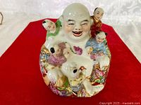 Front view of porcelain laughing Buddha with children figurine