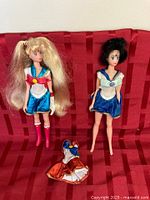 Full view of both dolls standing with spare outfit laid out