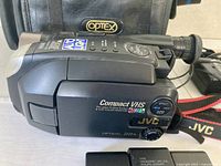 Left side profile of JVC camcorder showing model, 22x marking, and part of Optex bag