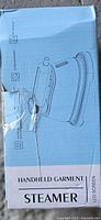 Front of blue box showing outline drawing of handheld garment steamer and text “Handheld Garment Steamer”
