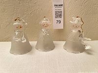 Front view of three frosted glass snowman bells showing faces, accessories, overall condition