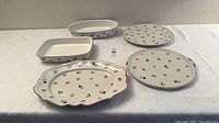 All five Petite Fleur pieces displayed: two platters, cake plate, oval casserole, square casserole