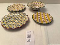 Four colourful MacKenzie Childs ceramic pieces displayed
