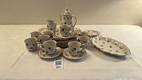 Full set displayed: teapot, creamer, nine cups and saucers, platters