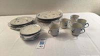 Stacked plates, cups and saucers showing quantity and pattern