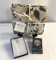 All three items: folded tablecloth with Spoonflower tag, boxed stick pin, boxed phone ring holder