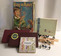 All items grouped: Hang On Harvey box, DIDO box, two Scrabble boxes, Nukeno box, wooden dominoes, Smurfs figurines