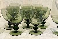 Group of 13 olive green crystal goblets showing color and quantity