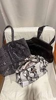 Three handbags displayed: grey tote, black shoulder bag, white/black satchel