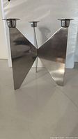 Front view of geometric stainless steel candelabra showing three taper cups and V-shape