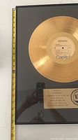 Full view of framed gold record with measuring tape showing height