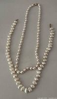 Two pearl strand necklaces laid out showing length and clasp types