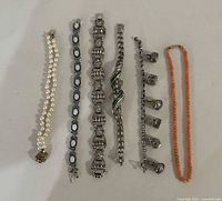 Six bracelets laid out side by side showing designs and materials