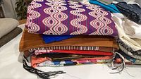 Stack of folded fabrics showing purple geometric top piece and various prints/solids below