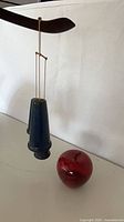 Two blue ceramic bells hanging beside red marble apple