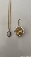 Necklace with opal ruby pendant and pearl brooch laid flat