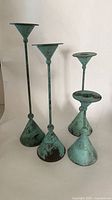 Four copper patina candlestick holders varying heights