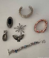 All seven jewellery pieces grouped: three brooches, one pendant, three bracelets