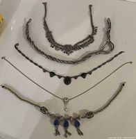 Five necklaces laid out showing designs and lengths