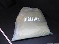 Both folded yellow vinyl boats, one in Airefina bag, measuring tape shown