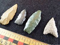 Four arrowheads lined beside ruler for scale
