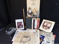 Group shot of all items including books, newspapers, figurine, stapler and accessories