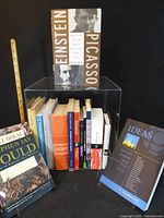 Front view showing majority of books lined inside acrylic cube with three featured volumes displayed