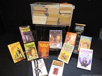 Entire lot showing plastic bin filled with paperbacks and several featured titles displayed