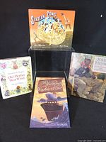 Group shot of four hardcover children's picture books standing and lying on clear stand