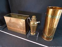 Front view of three copper items: rectangular box, small lidded pitcher, tall umbrella stand