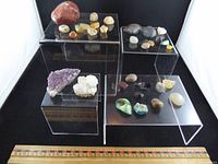 Overall lot showing all stones on acrylic risers with ruler for scale