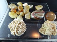 Group of yellow/orange tumbled stones, banded agate, desert rose, beige rock on acrylic riser
