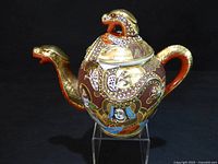 Oblique view showing snake spout, handle, lid finial, dragon and figure decoration