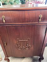 Full front view showing drawer, door with lyre carving, brass hardware and cabriole legs