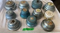 Group shot of eleven round music boxes varying lid decorations