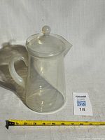 Coffee pot with lid assembled, tape measure showing height