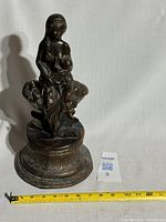 Full view of bronze statuette front with measuring tape for scale