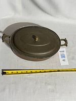 Top view of oval copper gratin pot with measuring tape for scale