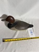 Full view of wooden duck decoy with measuring tape showing about 12 inches